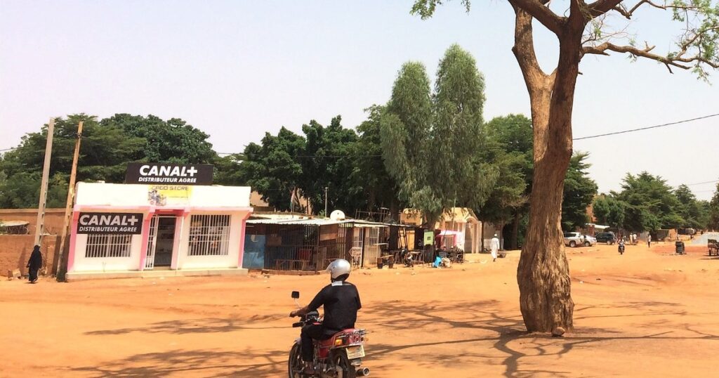 Boutique distributeur agree Canal+ dans une rue sahelienne, alors que le Burkina Faso sanctionne l'operateur