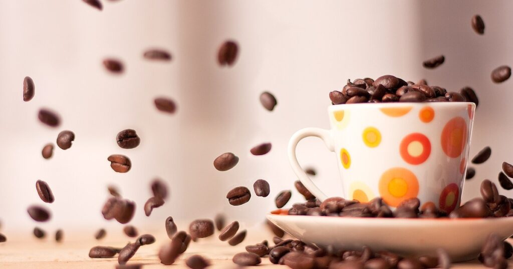 Grains de café torréfiés tombant dans une tasse, point où l'impôt européen frappe le café africain