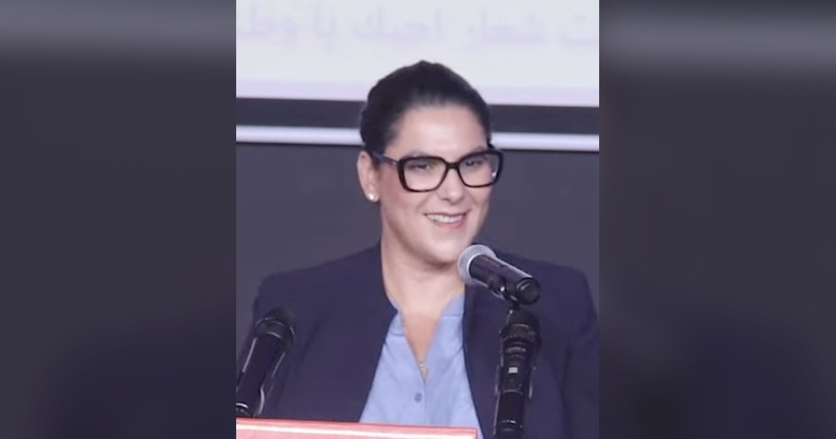 Fatima Ezzahra El Mansouri, en veste bleu marine et lunettes, s'exprimant au pupitre devant des micros, pour illustrer la formation du gouvernement El Mansouri